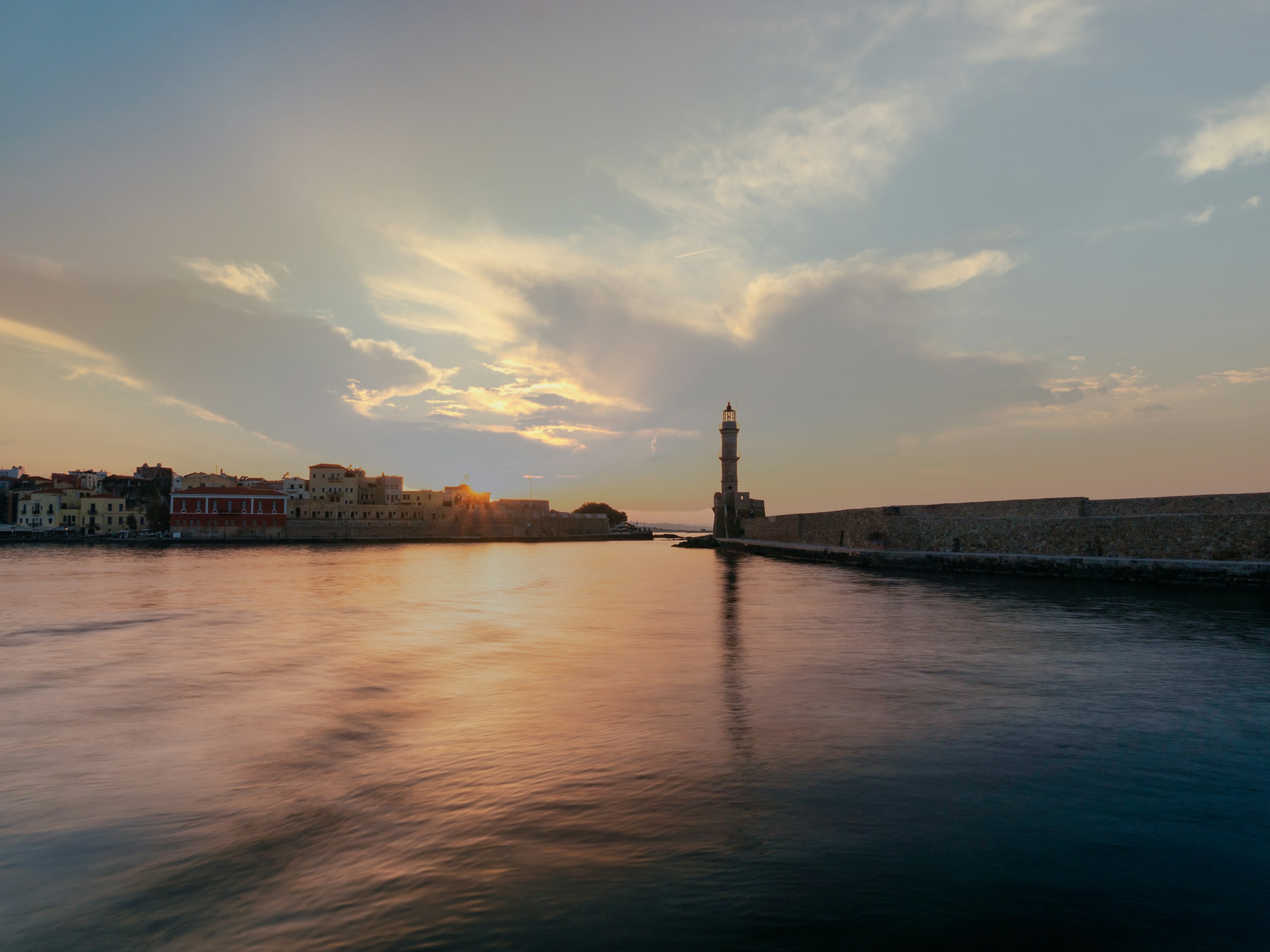 Evening light across the harbour, stone breakwater, and distant shoreline